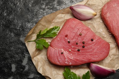 Raw tuna fillet with spices on black table, top view. Space for text