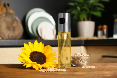 Photo of Sunflower, seeds and spray bottle with cooking oil on wooden table in kitchen