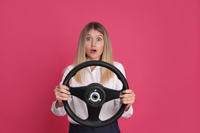 Photo of Emotional young woman with steering wheel on crimson background