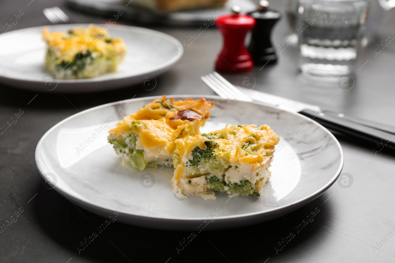 Photo of Pieces of tasty broccoli casserole on grey table