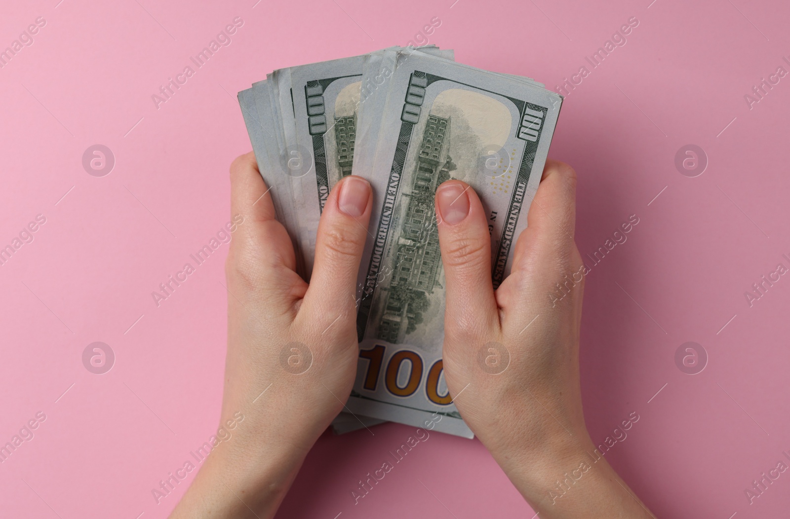 Photo of Money exchange. Woman holding dollar banknotes on pink background, top view