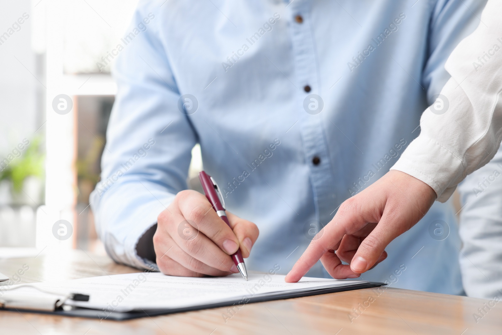 Photo of Businesspeople signing contract at table in office, closeup