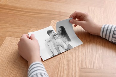 Image of Divorce and breakup. Woman ripping black and white photo at table, closeup