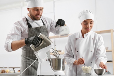 Pastry chefs preparing dough in mixer at kitchen table