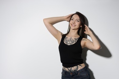 Portrait of smiling tattooed woman on light background. Space for text