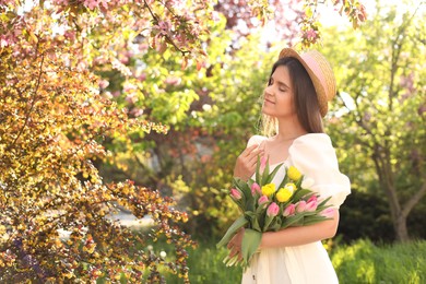 Photo of Beautiful young woman with bouquet of tulips in park on sunny day