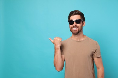 Photo of Portrait of smiling bearded man with stylish sunglasses on light blue background. Space for text