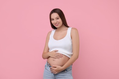 Photo of Beautiful pregnant woman with long hair on pink background