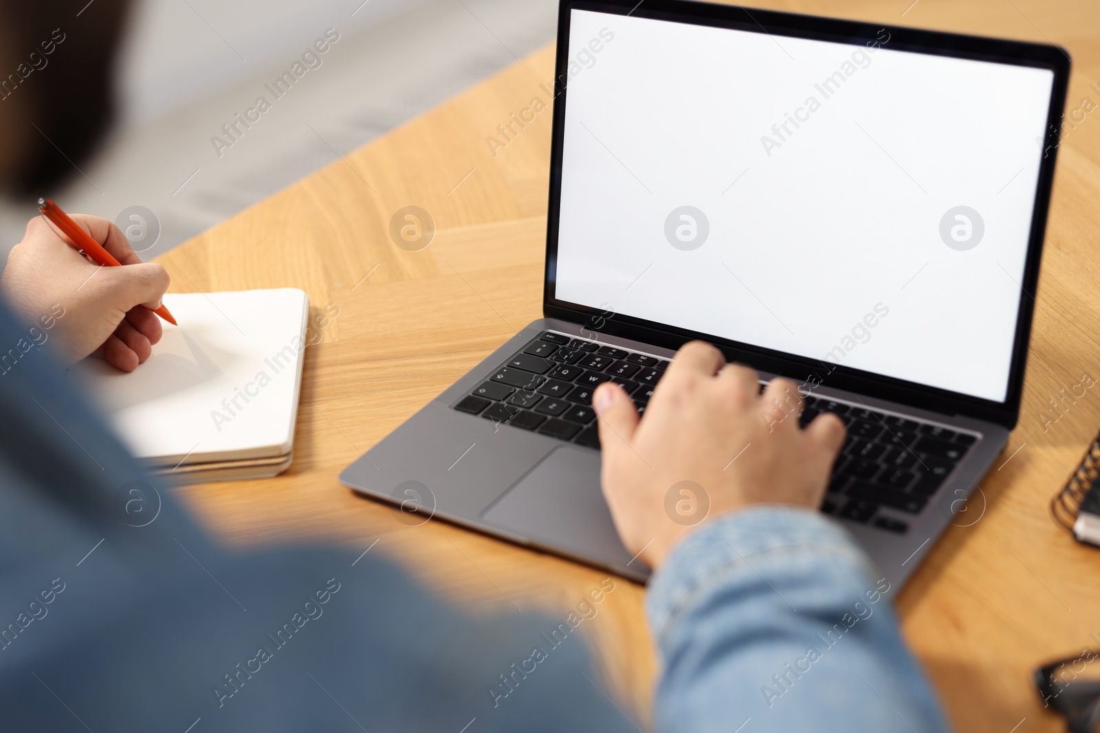 Photo of Young man watching webinar at table indoors, closeup