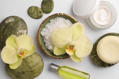 Photo of Flat lay composition with stones, spa products and beautiful flowers on white table