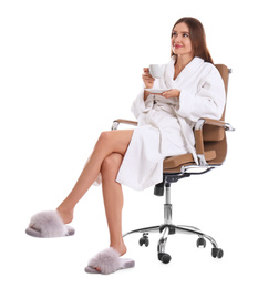 Young woman in bathrobe with cup of drink on white background