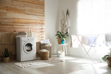 Photo of Stylish room interior with modern washing machine and drying rack