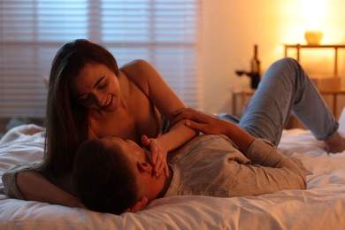 Passionate couple enjoying each other on bed indoors at night