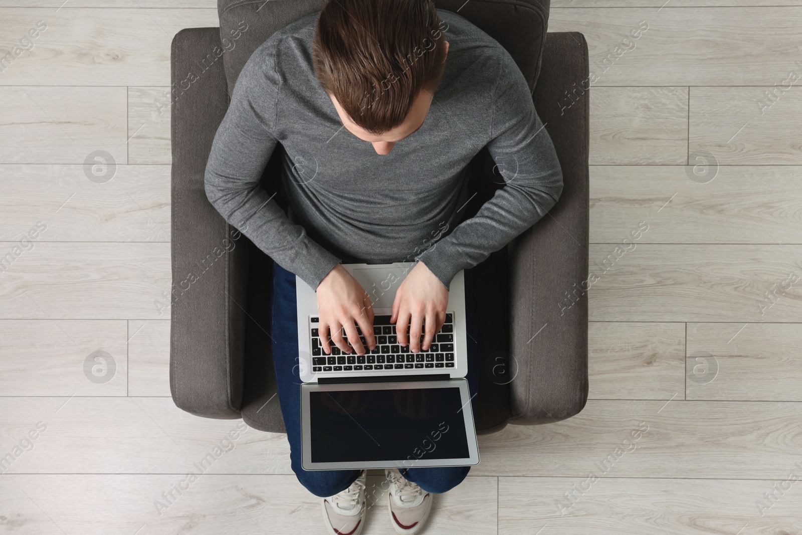 Photo of Man working with laptop in armchair, top view