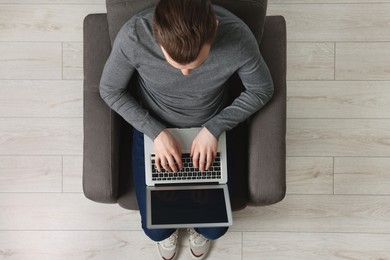 Man working with laptop in armchair, top view