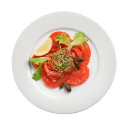 Photo of Salmon carpaccio with capers, lettuce, microgreens and lemon isolated on white, top view