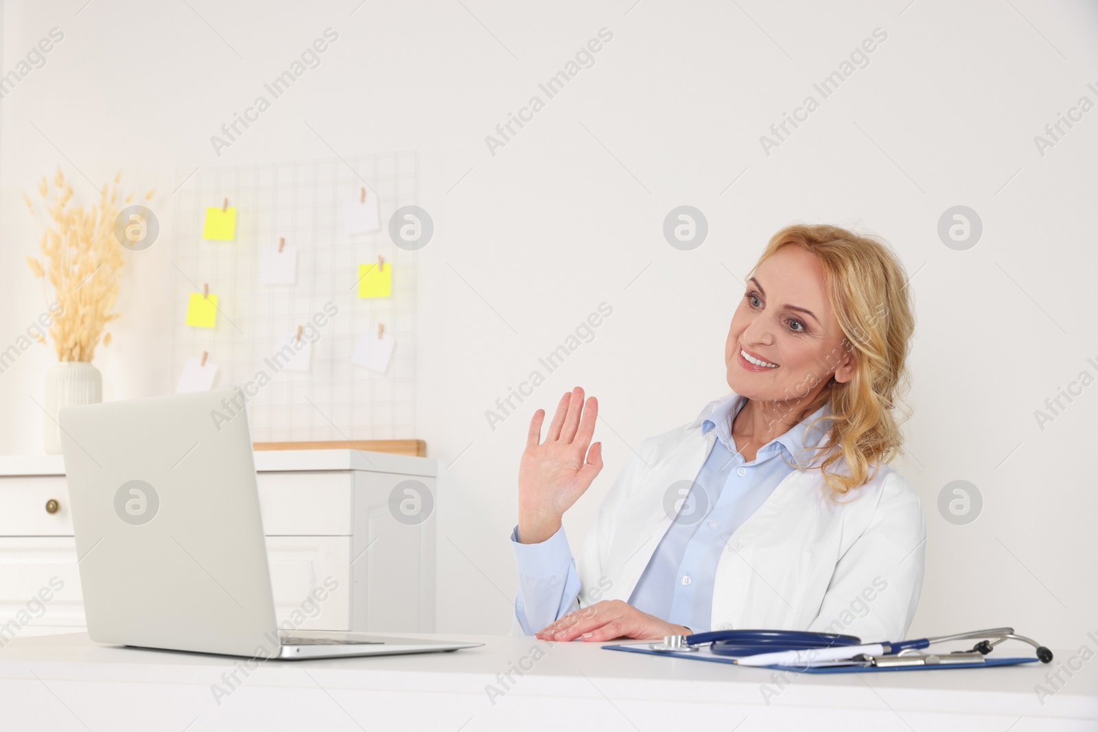 Photo of Doctor with laptop consulting patient in clinic. Online medicine concept