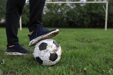 Photo of Man with dirty soccer ball on green grass outdoors, closeup. Space for text