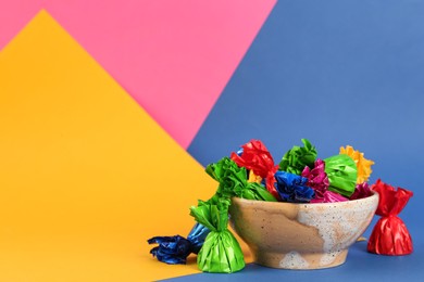 Candies in different wrappers on color background, space for text