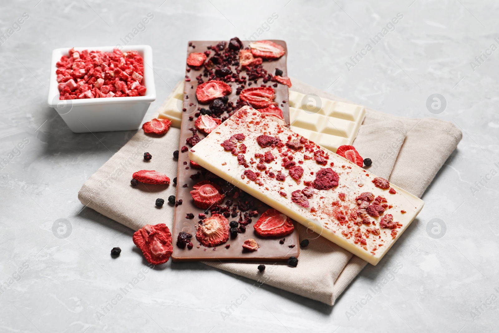 Photo of Different chocolate bars with freeze dried fruits on grey marble table