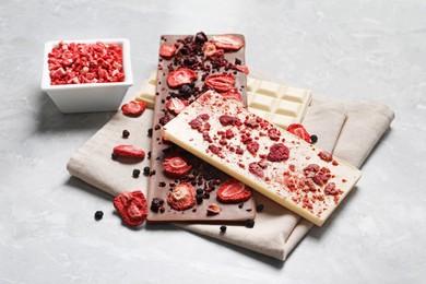 Photo of Different chocolate bars with freeze dried fruits on grey marble table