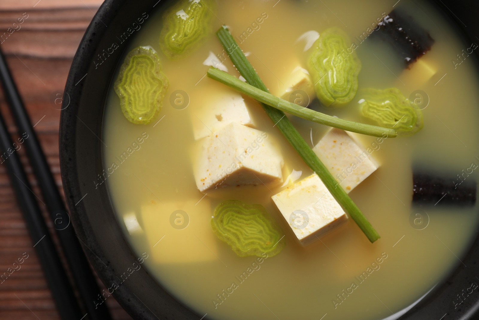 Photo of Bowl of delicious miso soup with tofu served on table, top view