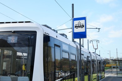 Modern streetcar near tram stop sign outdoors