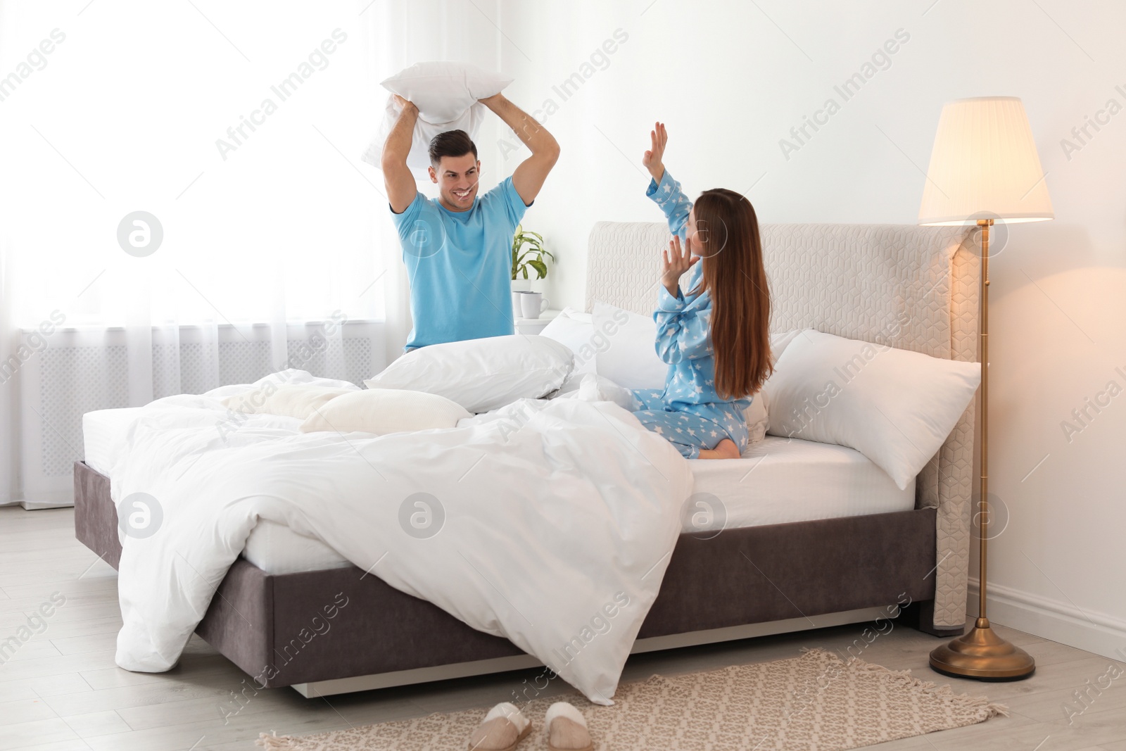 Photo of Happy couple having pillow fight in bedroom
