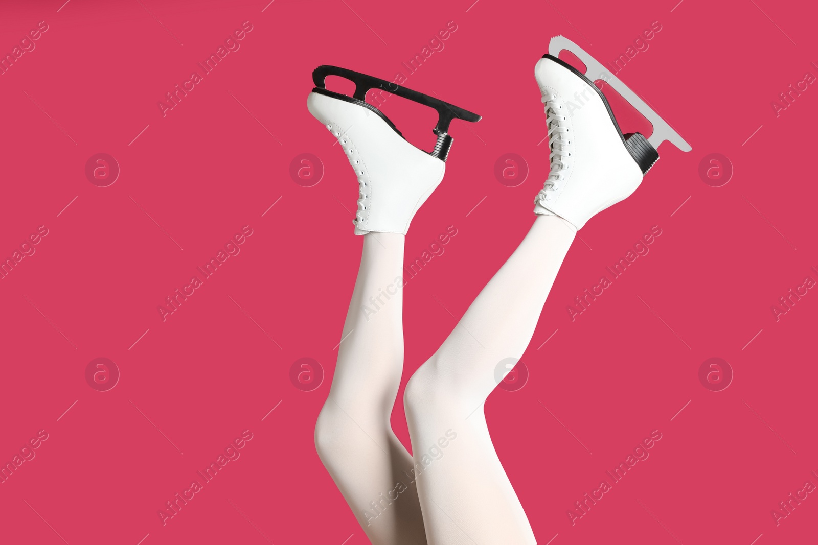 Photo of Woman in elegant white ice skates on pink background, closeup of legs
