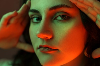 Portrait of beautiful young woman on color background with neon lights, closeup