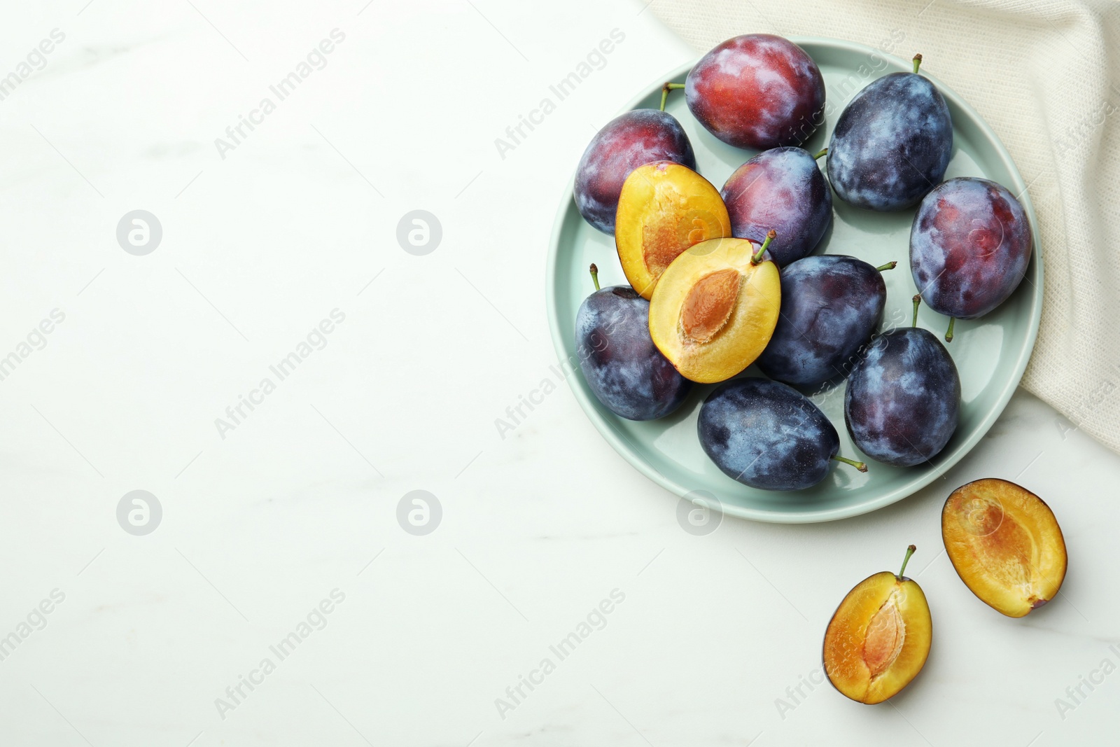 Photo of Tasty ripe plums on white table, flat lay. Space for text