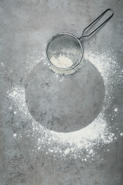 Photo of Flour and strainer on light grey table, top view. Space for text
