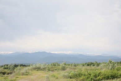 Photo of Picturesque view of mountains and field on cloudy day