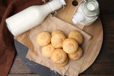 Photo of Tasty sweet sugar cookies and milk on wooden table, top view