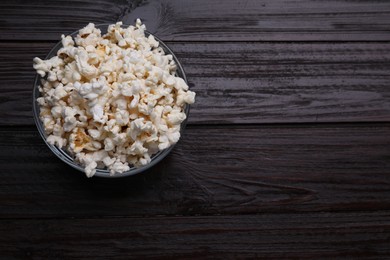 Tasty popcorn on black wooden table, top view. Space for text