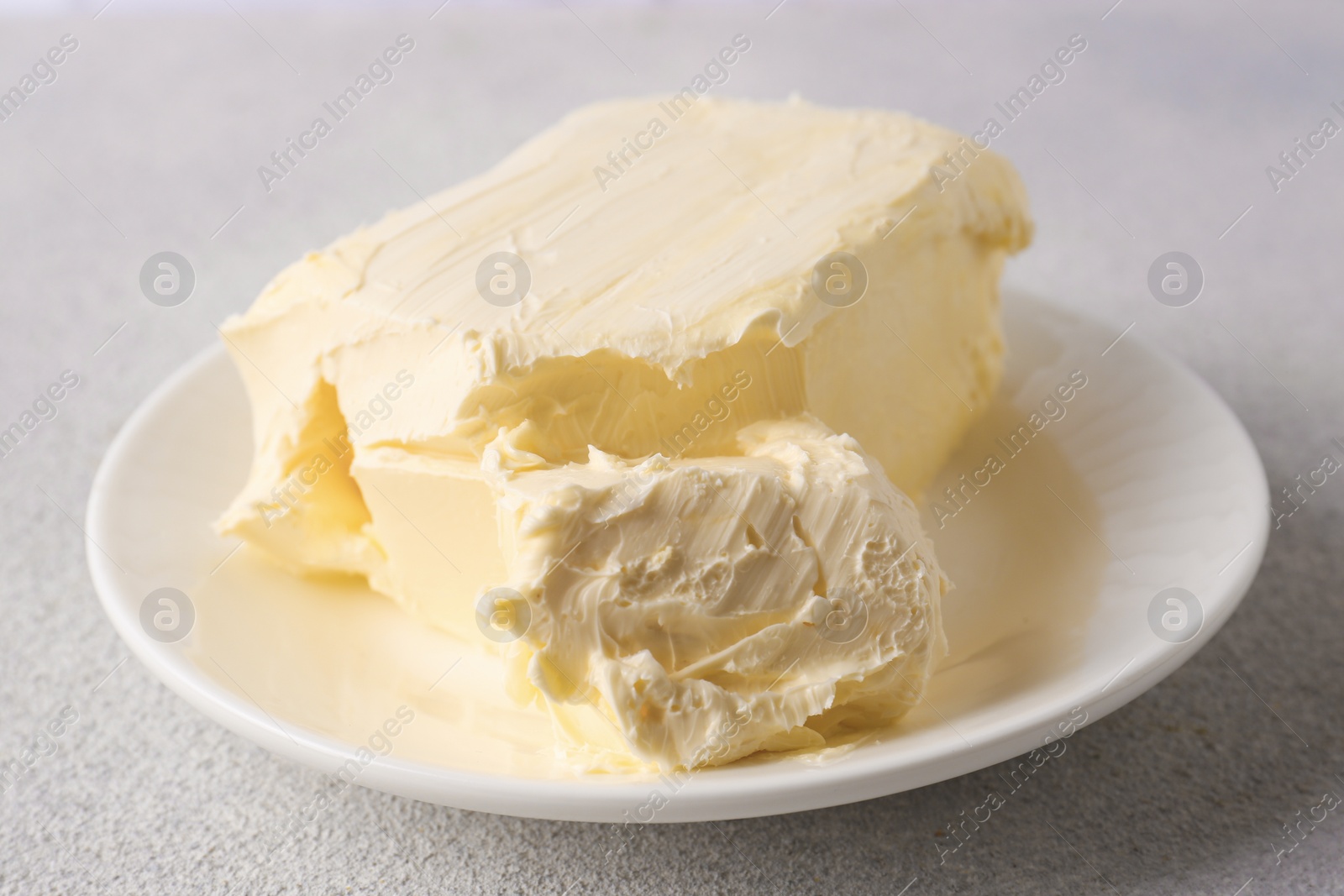 Photo of Plate with tasty homemade butter on white textured table