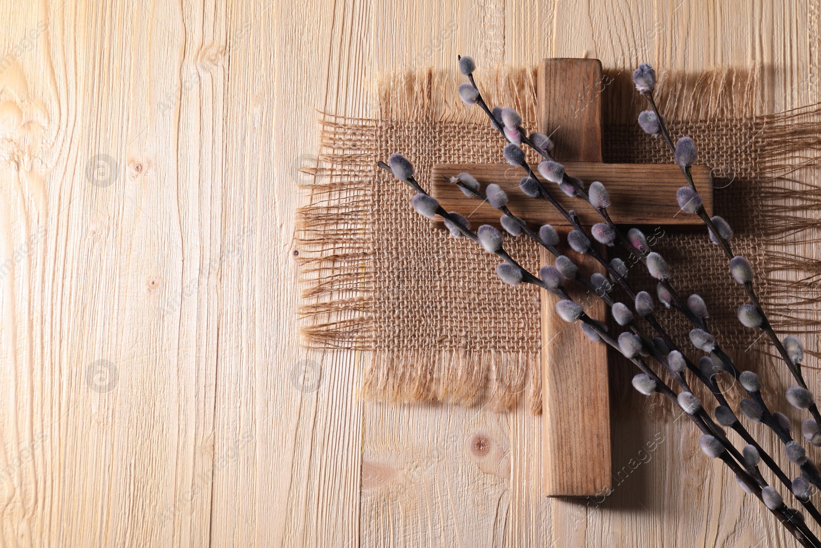 Photo of Cross and willow branches on wooden background, flat lay. Space for text