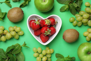 Photo of Fresh ripe strawberries, apples, grape, kiwis and mint on green background, flat lay