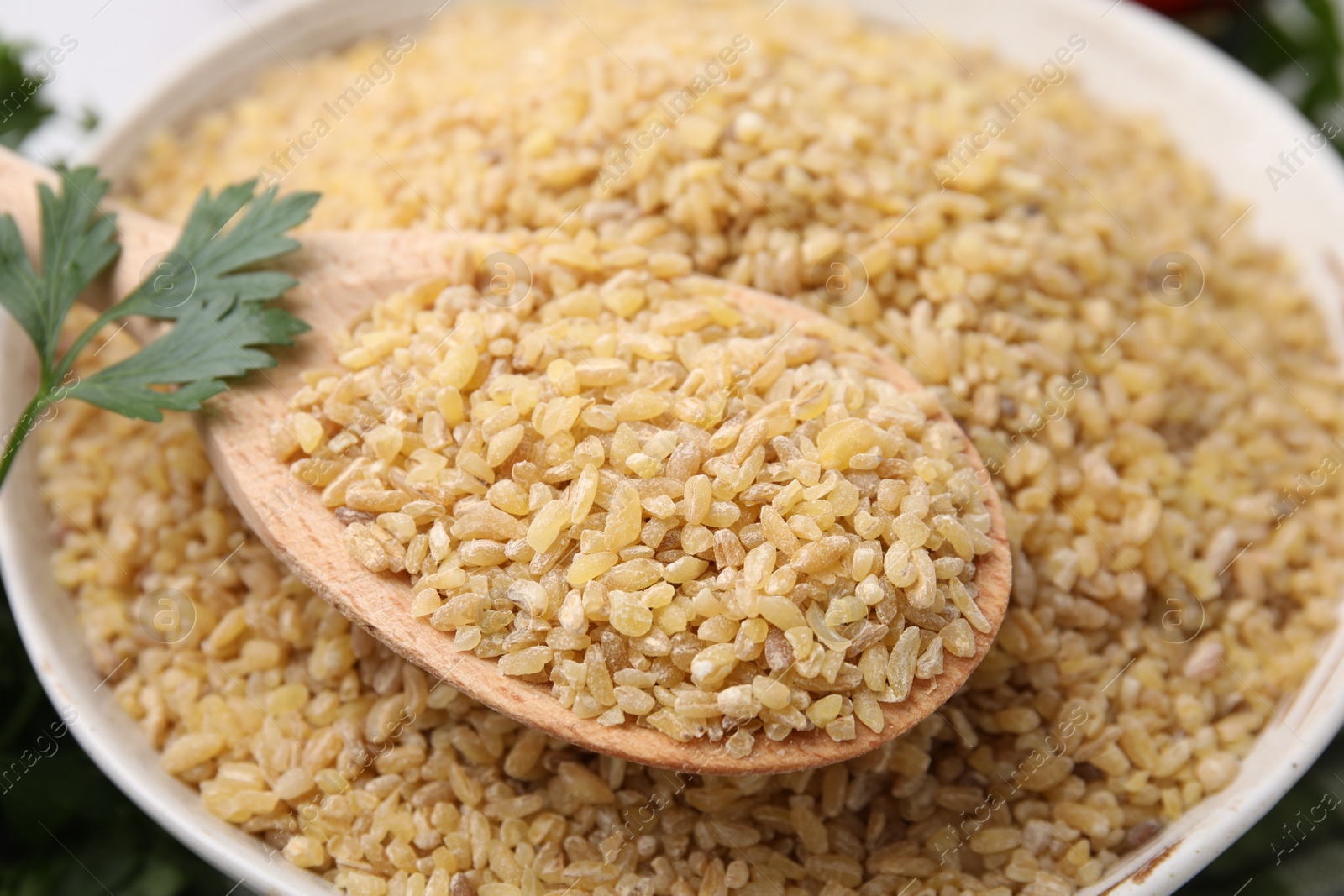 Photo of Bowl and spoon with raw bulgur, closeup