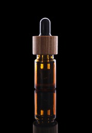 Photo of One brown bottle with tincture on mirror surface against black background