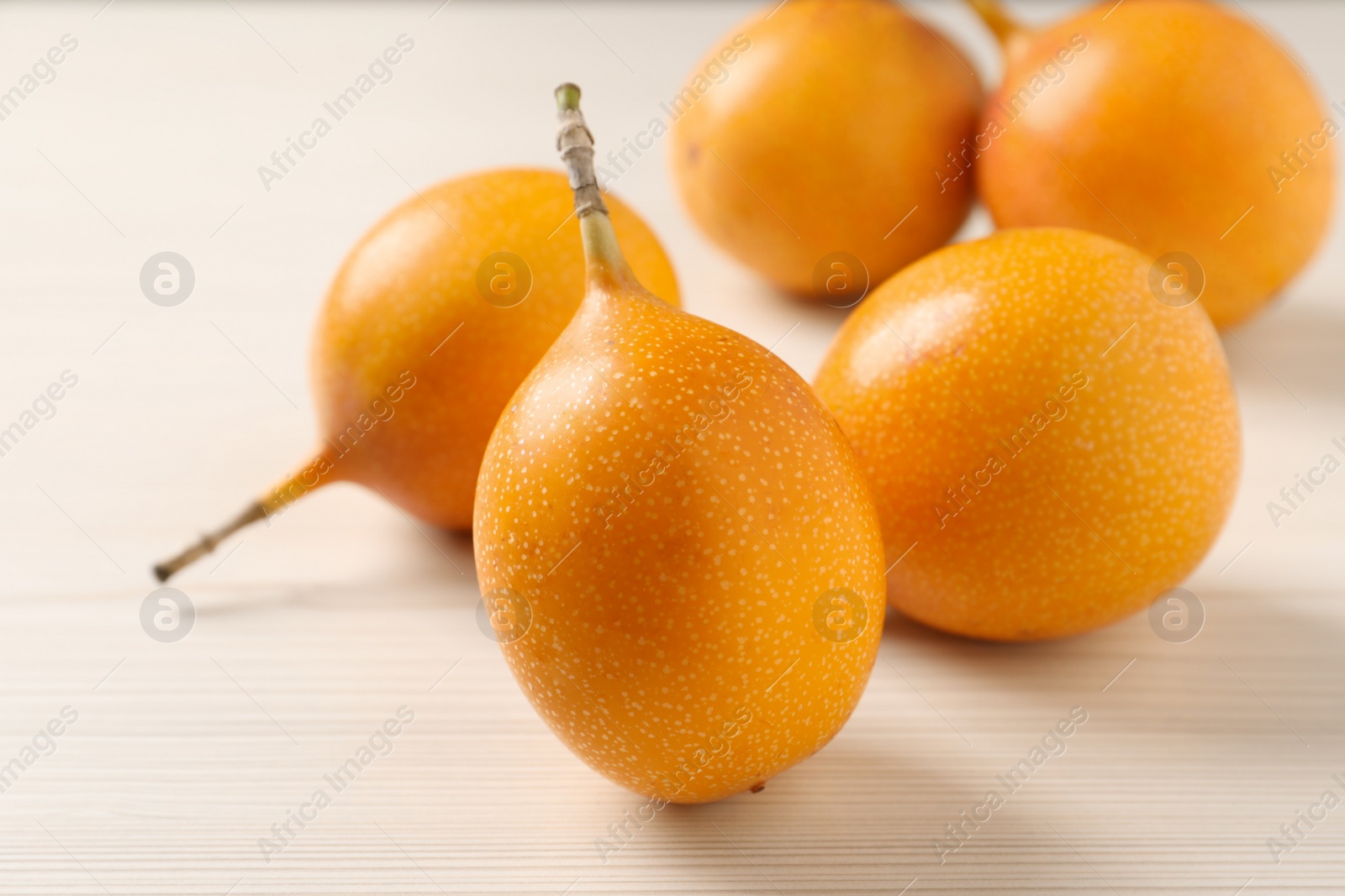 Photo of Delicious ripe granadillas on white wooden table, closeup