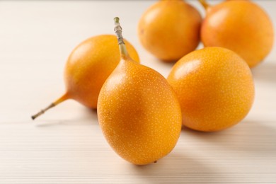 Photo of Delicious ripe granadillas on white wooden table, closeup