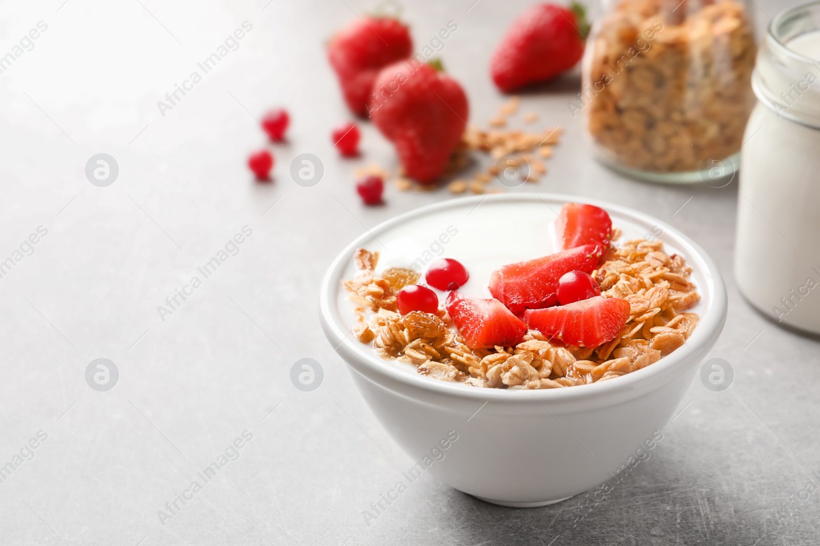 Photo of Bowl with yogurt, berries and granola on table