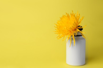 Photo of Medicine bottle and flower on yellow background, space for text