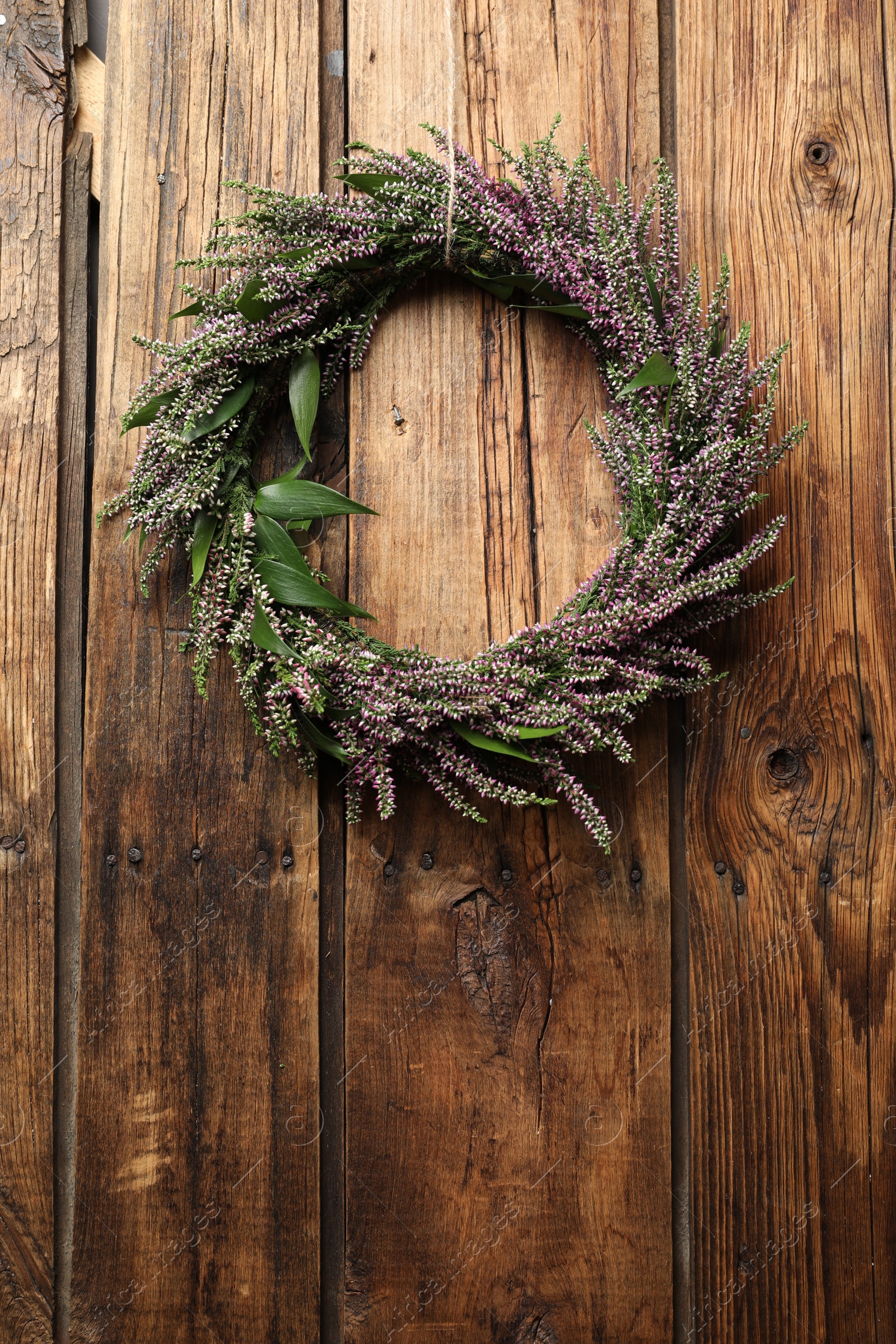 Photo of Beautiful autumnal wreath with heather flowers on wooden background, top view. Space for text