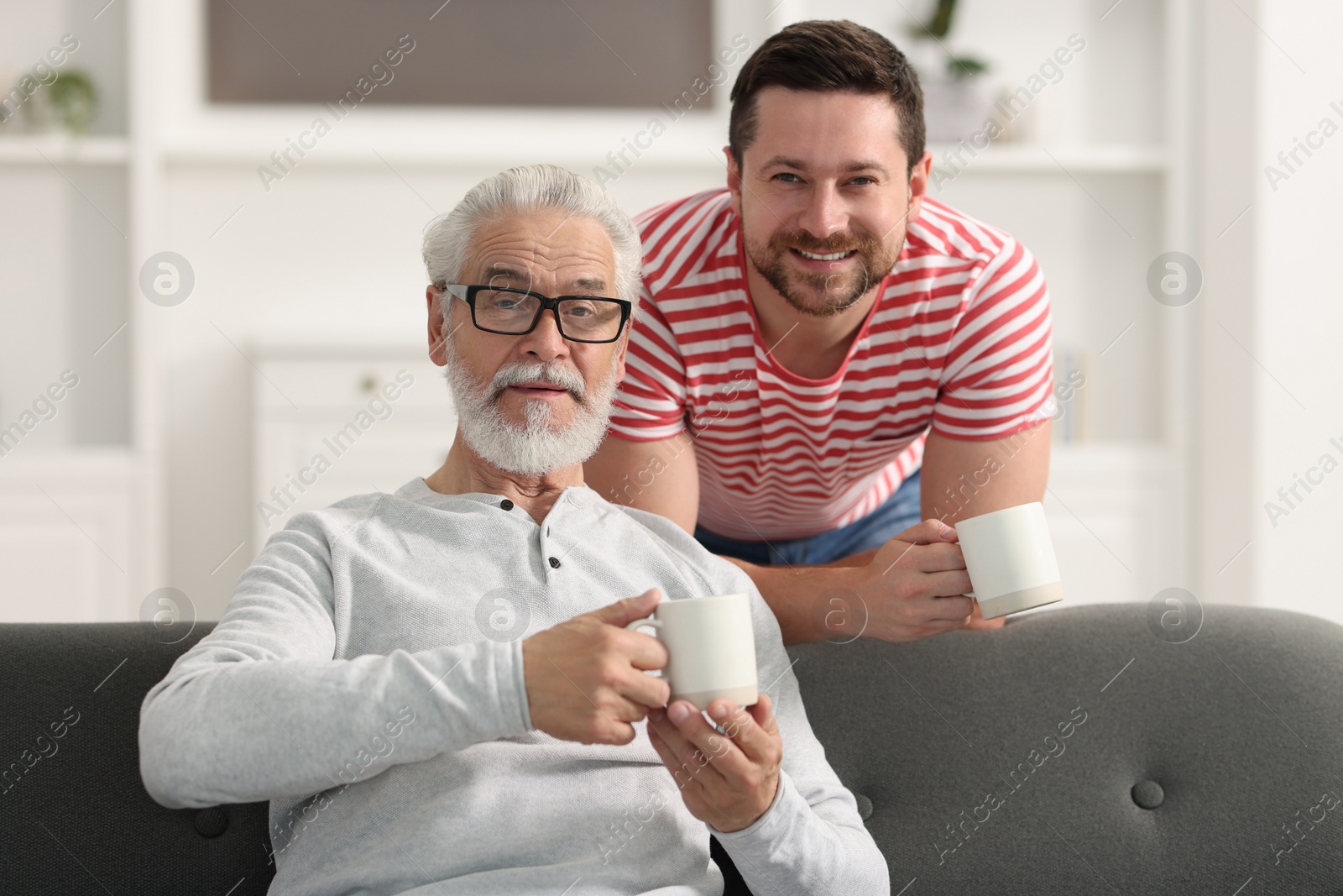 Photo of Happy son and his dad with cups at home