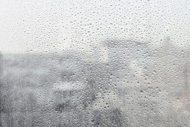 Photo of Blurred view of city from window on rainy day