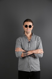 Photo of Young man with stylish tattoos on grey background