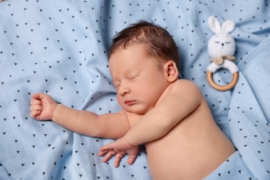 Cute newborn baby with toy bunny sleeping on bed