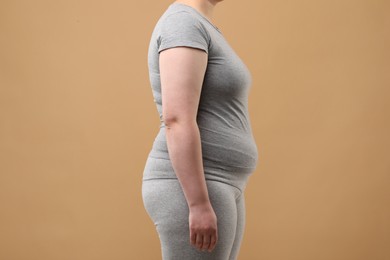 Overweight woman in grey clothes on beige background, closeup